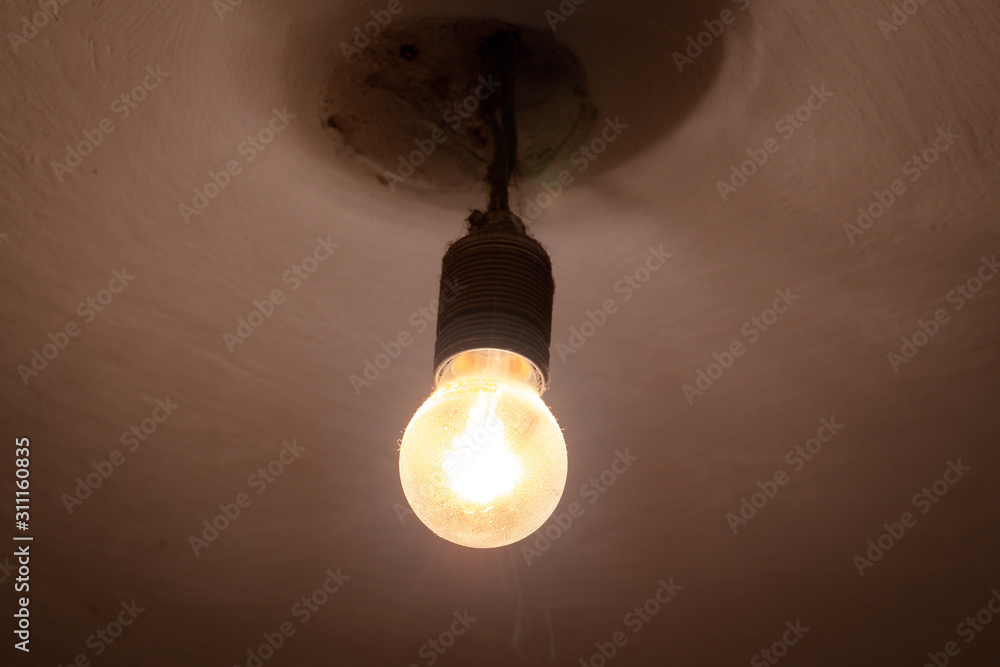 shining old light bulb hanging on a shabby ceiling. The concept of price increases shining old light bulb hanging on a shabby ceiling. The concept of price increases