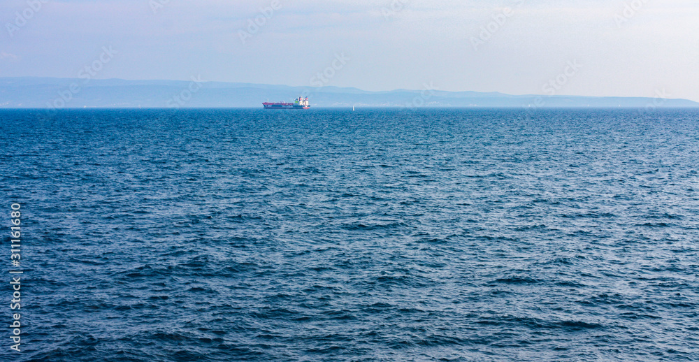 Seascape view of a distant tanker ship on a vast blue sea during travel in Croatia