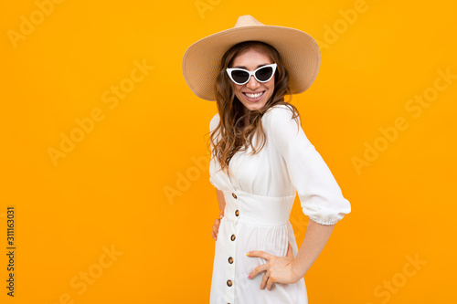 portrait of a charming glamorous beautiful girl in a straw hat and glasses on a yellow background