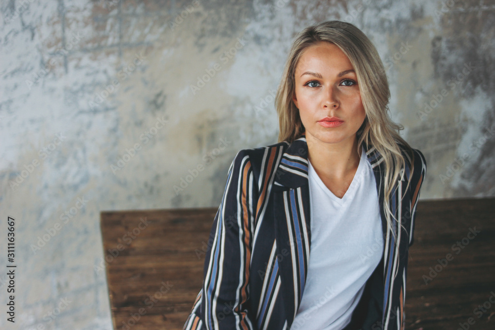 Beautiful smiling blonde friendly young woman businesswoman in casual clothing in loft modern office Beautiful smiling blonde friendly young woman businesswoman in casual clothing in loft modern office