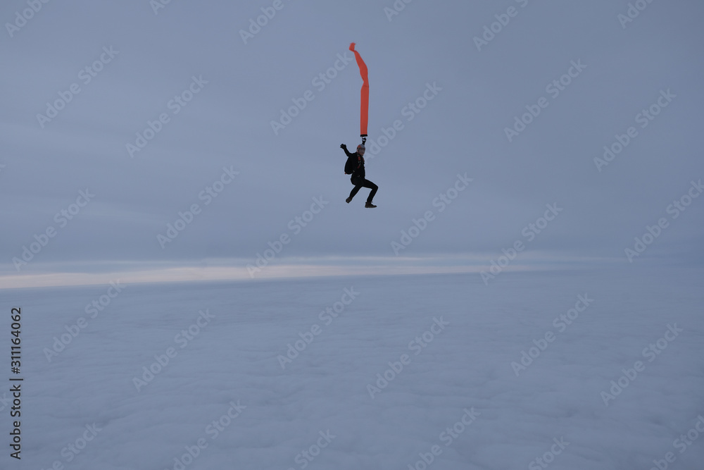 Skydiving. Skydiver with an orange ribbon in the winter sky