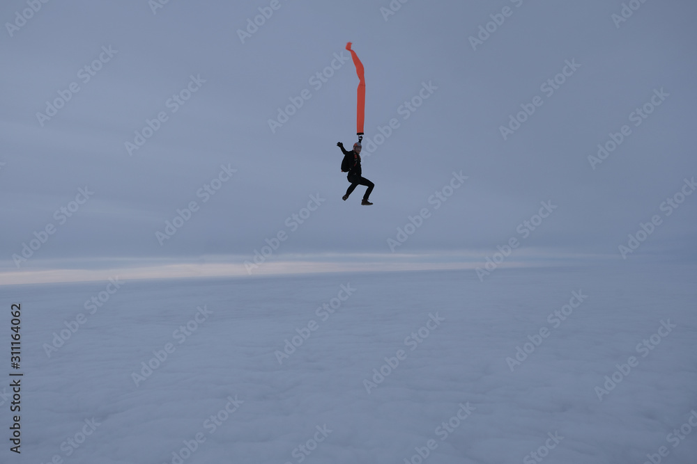 Skydiving. Skydiver with an orange ribbon in the winter sky Skydiving. Skydiver with an orange ribbon in the winter sky
