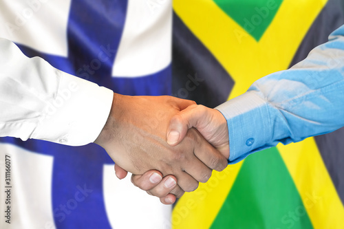 Handshake on Finland and Jamaica flag background.