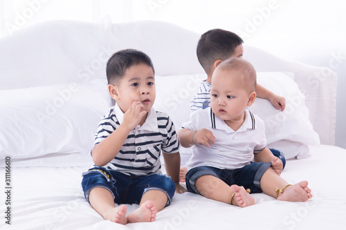 Selective focus twin adorable boys kids happy playing together on bed at home, Asian twin brother and sibling baby cute boy spent time sit together on bed at home, preschool kids boy playing on bed