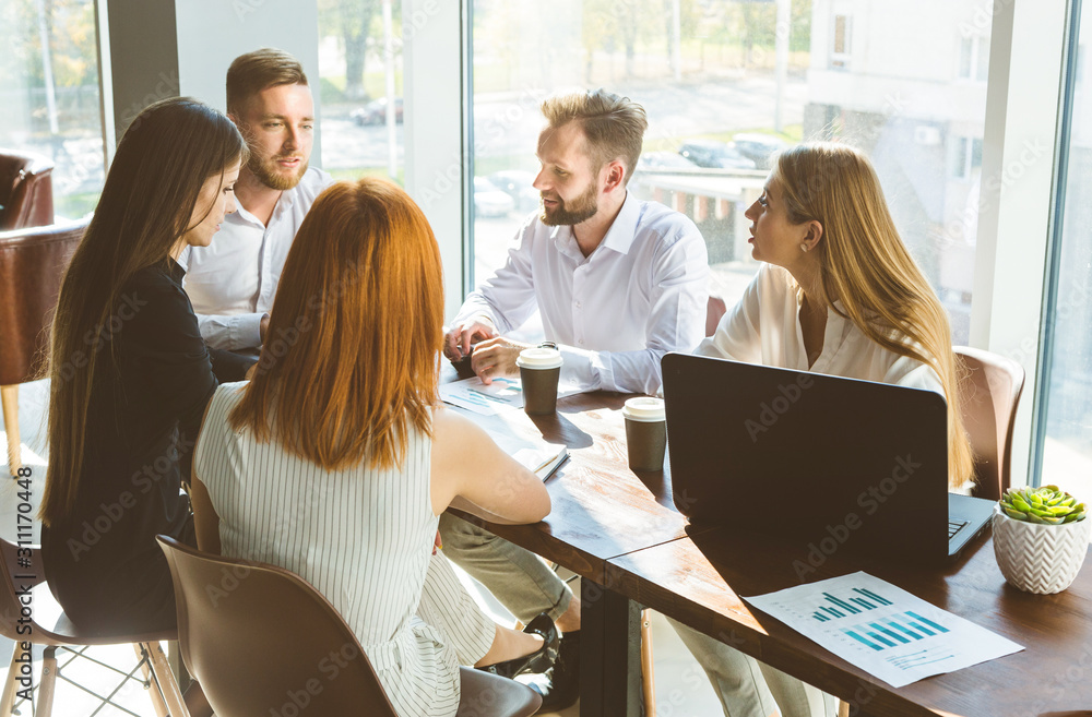 A team of young businessmen working and communicating together in an office. Corporate businessteam and manager in a meeting.