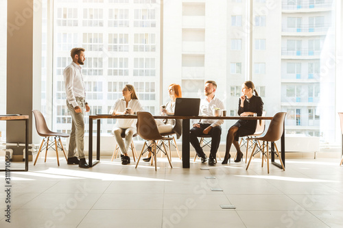 A team of young businessmen working and communicating together in an office. Corporate businessteam and manager in a meeting. desktop against the background of the pan window, free space for text