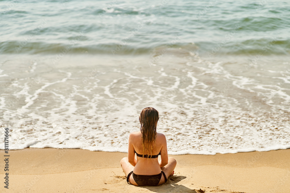 A Young girl is relaxing on the beach. The girl practices yoga A Young girl is relaxing on the beach. The girl practices yoga