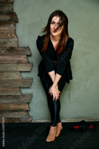 Wallpaper Mural The concept of a glamorous portrait. Portrait of a pretty brunette girl in a black fashion suit on a stylish background in the original interior. Stands in front of the camera in various poses. Torontodigital.ca