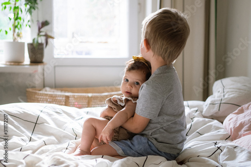 little infant baby girl sitting together with her toddler brother