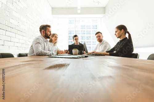 A team of young businessmen working and communicating together in an office. Corporate businessteam and manager in a meeting.