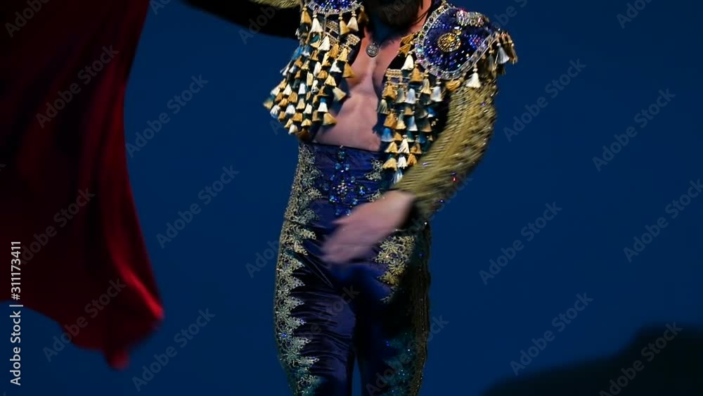 Torero in blue and gold suit or typical spanish bullfighter isolated spotlight on a blue background. Close up, slow motion. Torero in blue and gold suit or typical spanish bullfighter isolated spotlight on a blue background. Close up, slow motion.