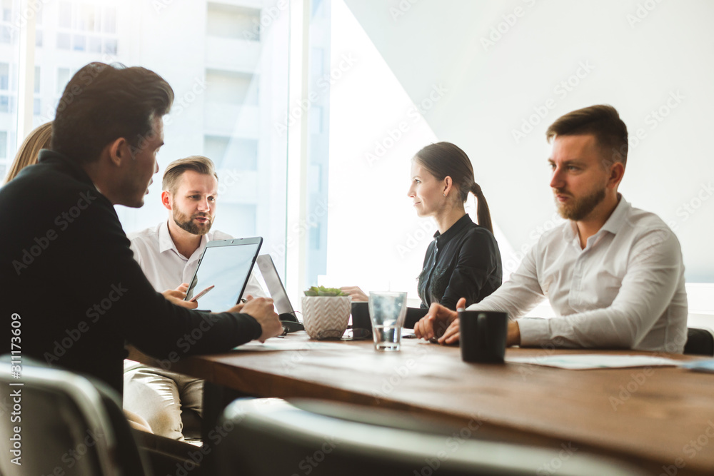 A team of young businessmen working and communicating together in an office. Corporate businessteam and manager in a meeting. A team of young businessmen working and communicating together in an office. Corporate businessteam and manager in a meeting.