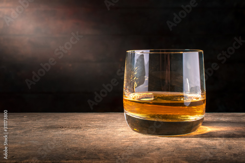 Glass of whiskey  on wooden table with copy space
