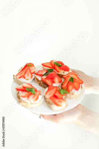Sweet cheese and strawberry toasts on the white plate on neutral background