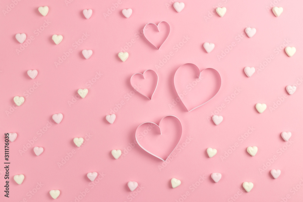 Composition for Valentine's Day February 14th. Delicate pink background and a heart cut out of paper. Heart shaped yellow and pink marshmallows. Greeting card. Flat lay, top view, copy space