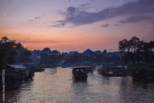 Fisherman boat driving through floating native floating village on pylons Kampong Phluk in Cambodia Asia