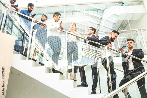 young business people arego down the stairs and talking on the background of glass offices. Corporate businessteam and manager in a meeting.