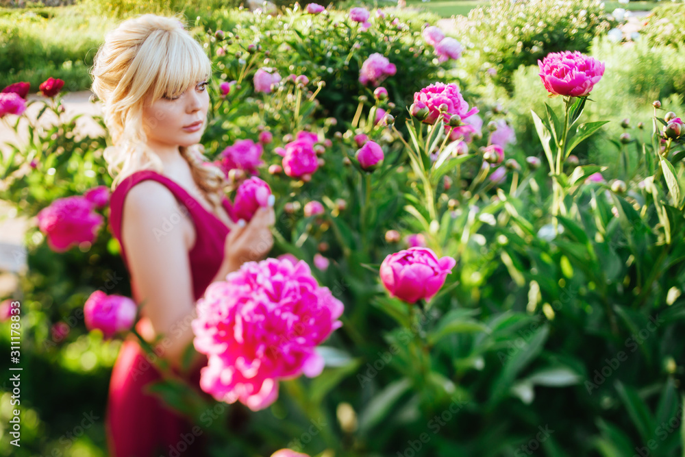 Outdoor close up portrait of beautiful young woman with long blonde hair, makeup, posing in the blooming garden. Female spring fashion concept Outdoor close up portrait of beautiful young woman with long blonde hair, makeup, posing in the blooming garden. Female spring fashion concept