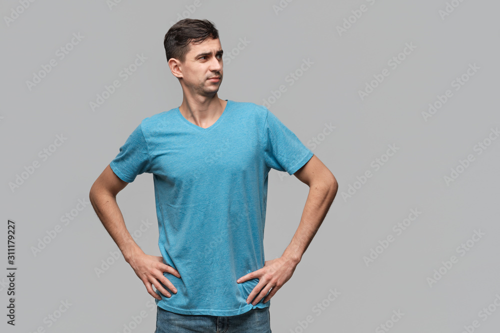 Confident man in a blue tee looking up holding hands on hips. Concept of confidence. Confident man in a blue tee looking up holding hands on hips. Concept of confidence.