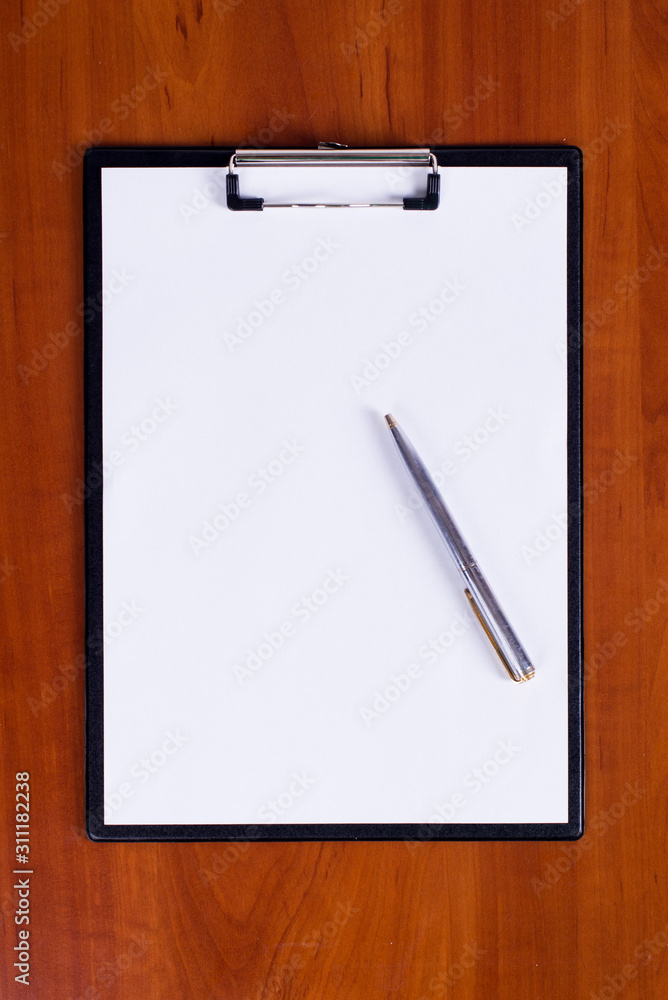Clipboard with pen on a wooden table Clipboard with pen on a wooden table