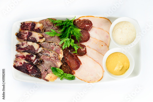 plate with a set of sausages and ham decorated with basil and sauce