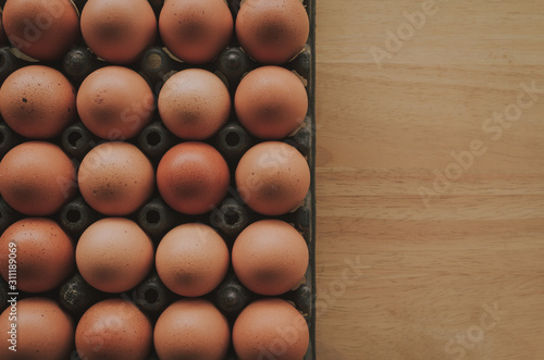 Top view of raw eggs in plastic tray on wooden desk with copy space 