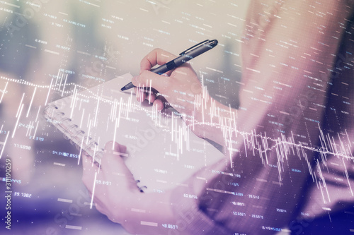 Multi exposure of hands making notes with forex chart huds. Stock market concept.