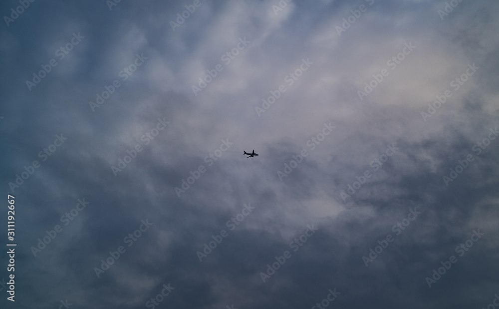 A Jet Flies High Above Beneath A Cloudy Sky