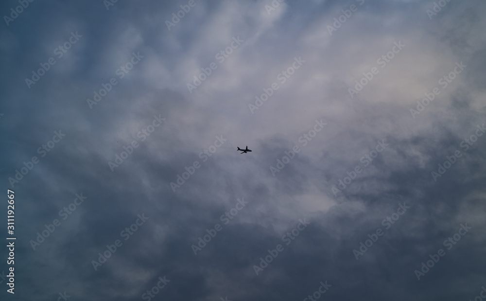 A Jet Flies High Above Beneath A Cloudy Sky A Jet Flies High Above Beneath A Cloudy Sky