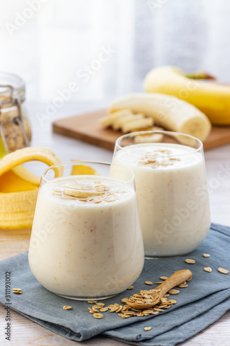 Vegan banana and oatmeal smoothie in glass jar on the light background. Healthy food.