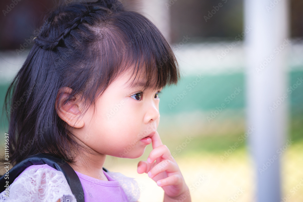 Portrait Asian baby child girl is putting a finger into mouth. The index finger is in the mouth. Picking teeth, wore a purple shirt, the sleeves were lace fabric. Her hair is beautifully braided. Portrait Asian baby child girl is putting a finger into mouth. The index finger is in the mouth. Picking teeth, wore a purple shirt, the sleeves were lace fabric. Her hair is beautifully braided.