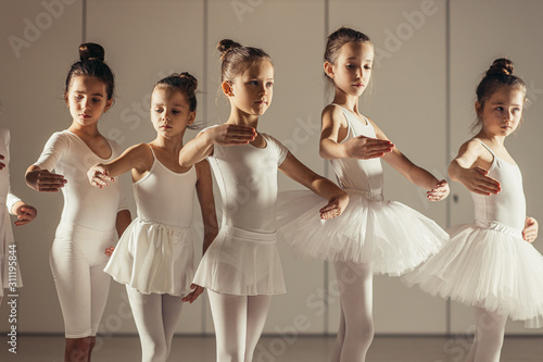 Young caucasian ballerinas stretching before performance isolated in classical dance school, young professional dancers