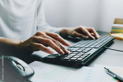 2 hands of Asian woman is press, typing on 2 language keyboard as Thai and English. Maybe preparation about information to report, chat to lover or shopping online by connect to internet at home, cafe photo