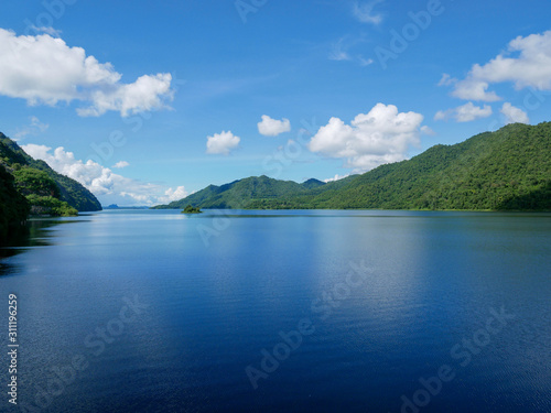 View from Vachiralongkorn Dam, Kanchanaburi, Thailand. Water and the blue sky in the background is a green mountain.