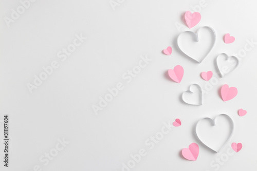 Composition for Valentine's Day February 14th. Delicate composition of pink hearts made of paper on a white background. Heart cut out of paper. Greeting card. Flat lay, top view, copy space. © photo_mts
