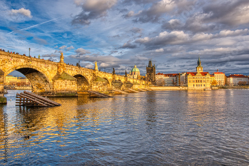Beautifully illuminated Charles Bridge at sunset with surrounding buildings, Prague