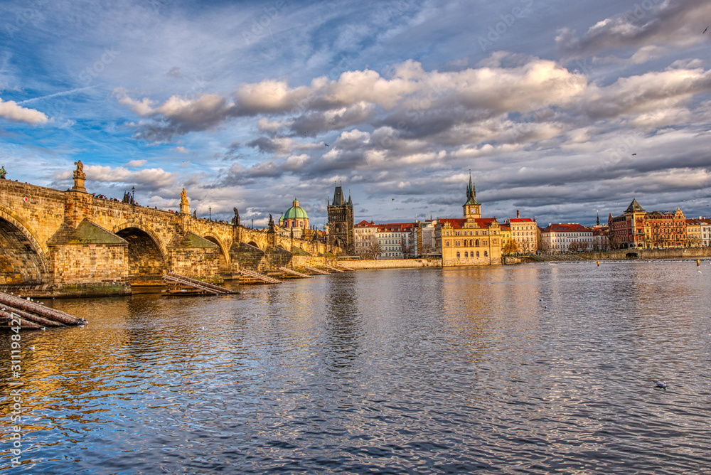 Beautifully illuminated Charles Bridge at sunset with surrounding buildings, Prague