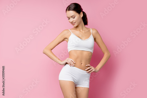 Health body concept. young attractive woman with perfect body stand wearing white sports undewear isolated on pink background photo
