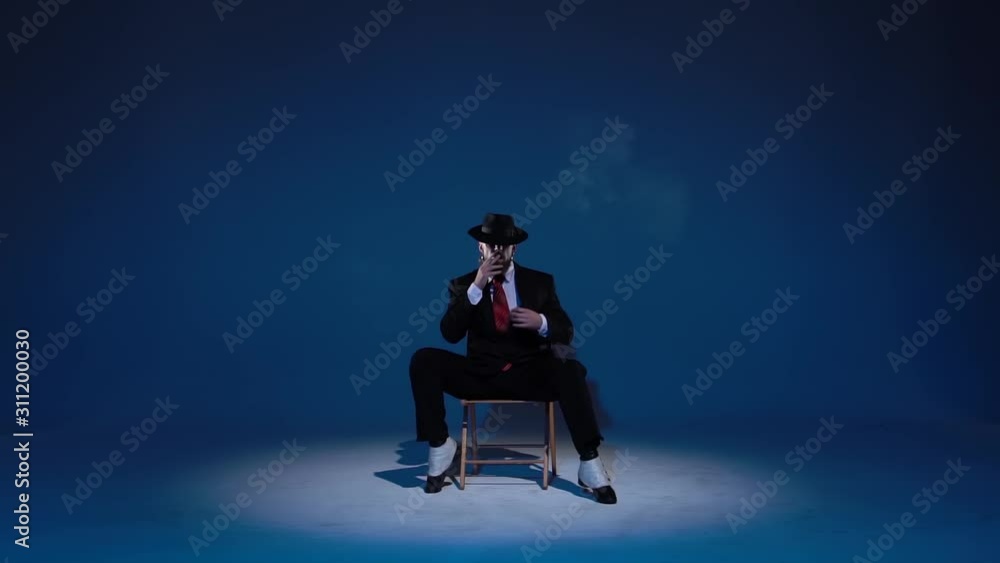 Elegant man in a black hat is dancing an erotic dance. Spotlight on a blue background. Close up, slow motion. Elegant man in a black hat is dancing an erotic dance. Spotlight on a blue background. Close up, slow motion.