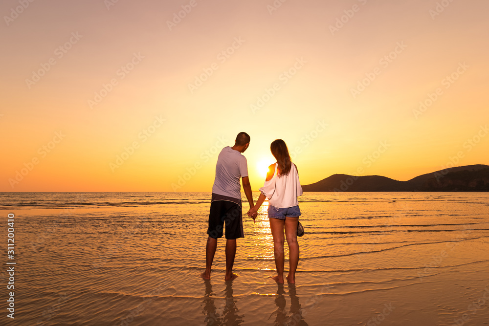 couple hand hold on the beach between sunset.