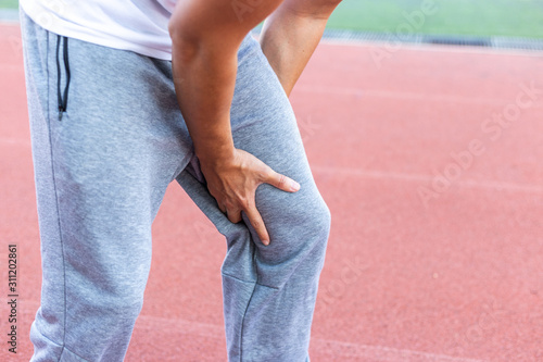 Athlete suffering form running knee or kneecap injury during outdoor workout.