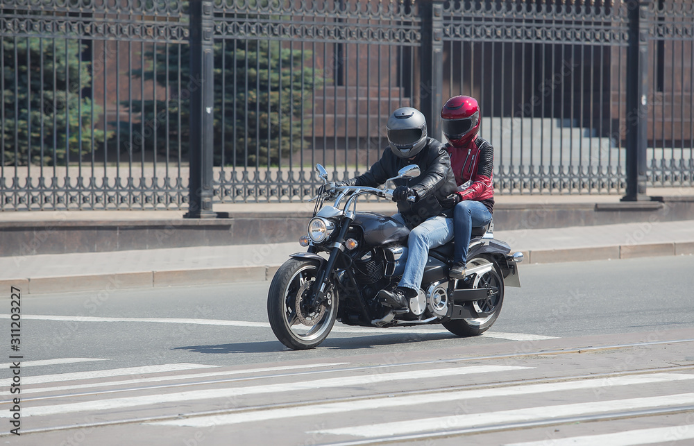 man and a woman on a motorcycle in helmets ride on a street