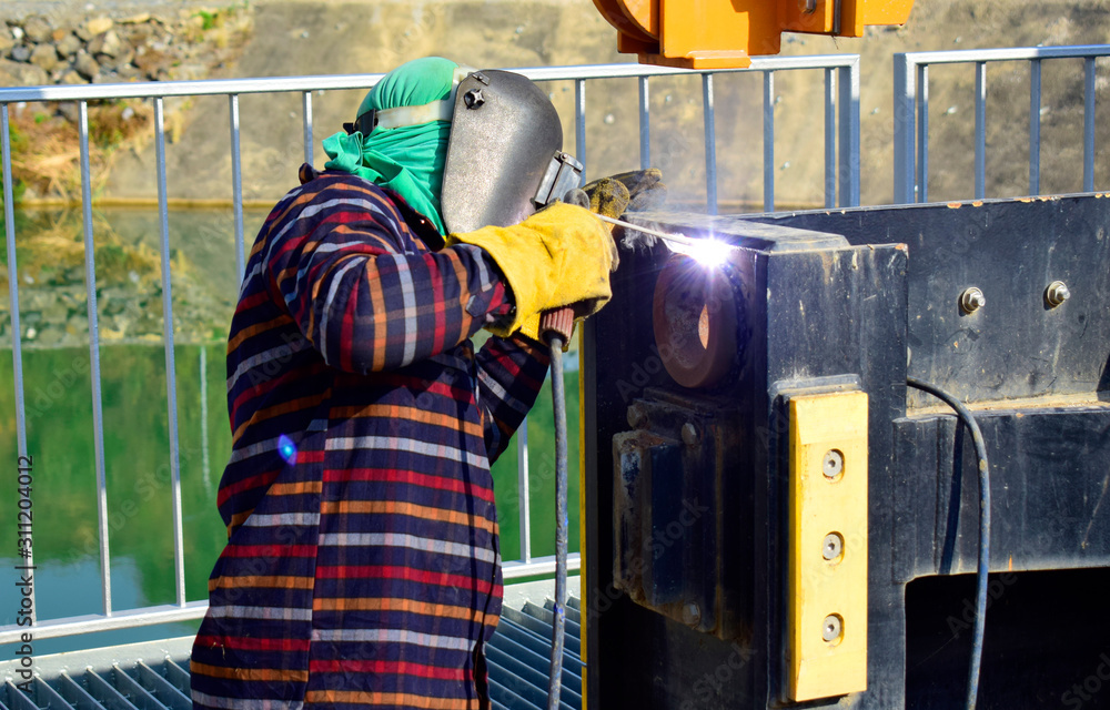 The welder working to welding the bushing of stoplock sluice the dam,December 2019