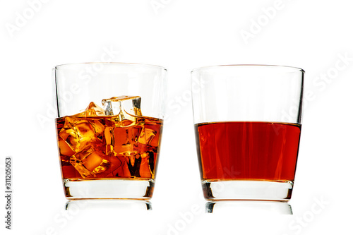 A glass of whiskey with ice or brandy and a square carafe isolated on a white background. Whiskey with ice in a glass against white background.