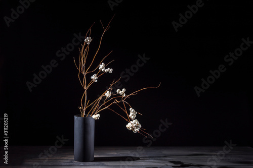 Branch of a bush of a snowberry in a vase on a dark background. Ikebana. photo