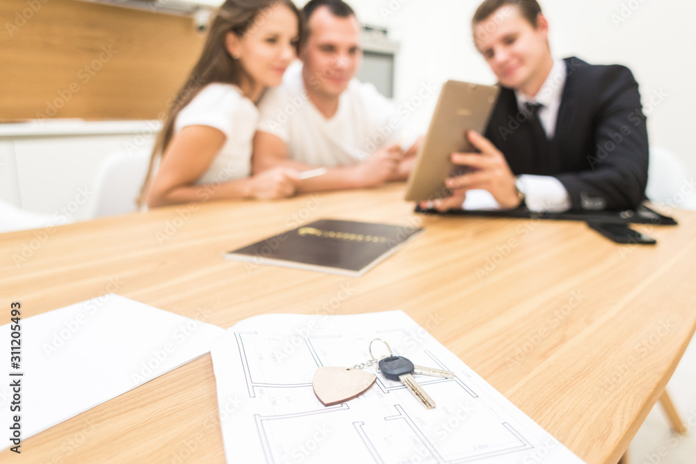 real estate agent is selling an apartment to a young family. conclusion of a lease and purchase of a house, apartment. man shows housing real estate agent is selling an apartment to a young family. conclusion of a lease and purchase of a house, apartment. man shows housing