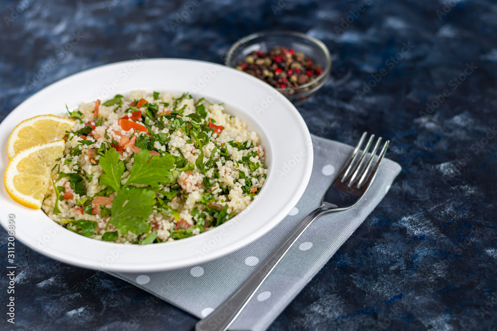Tabbouleh salad in a round plate on a wooden background. salad in a white plate on a dark blue, trendy background 2020. Tabbouleh salad in a round plate on a wooden background. salad in a white plate on a dark blue, trendy background 2020.