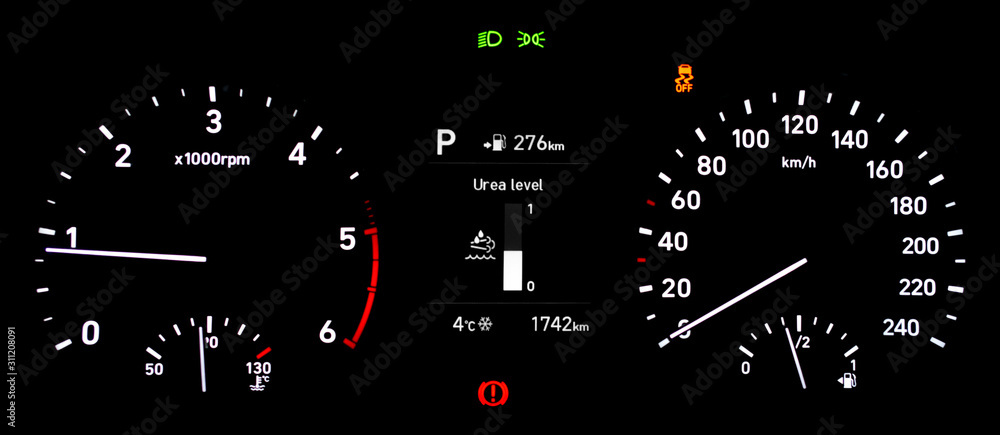 Car instrument panel with urea level indicator, speedometer, tachometer, odometer, fuel gauge, car temperature gauge, traction control and handbrake warning light. Photo on isolated background.