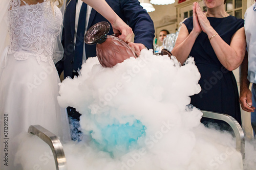 bride and groom make a cocktail of dry ice, alcohol and juice, glass with the effect of dry ice,blue cocktail with ice vapor, table with cocktails and dry ice