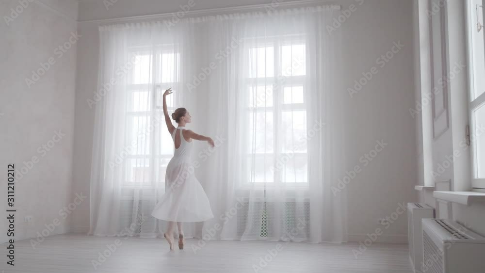 ballet dancer dancing in a light studio against the background of large windows ballet dancer dancing in a light studio against the background of large windows